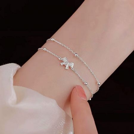 Close-up view of the double-layer 925 silver bracelet with a delicate bow charm.
