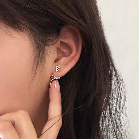 A detailed view of the intricate crisscross design of the silver bow earrings.