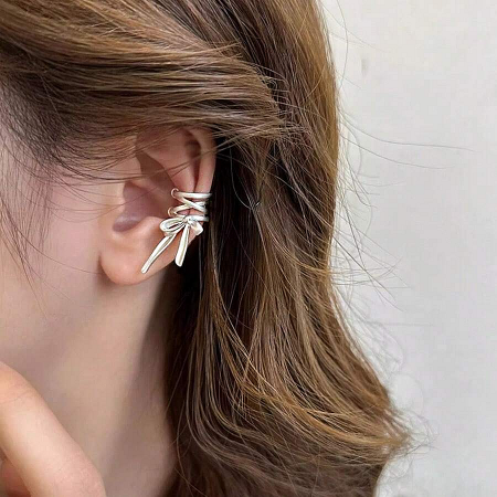Detailed close-up of the matte finish on the silver bow ear cuff.