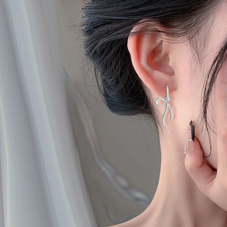 Close-up view of the sterling silver bow earring on a woman's ear, highlighting the CZ details.