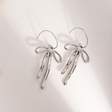 Product shot of the silver stainless steel bow drop earrings with long tails.