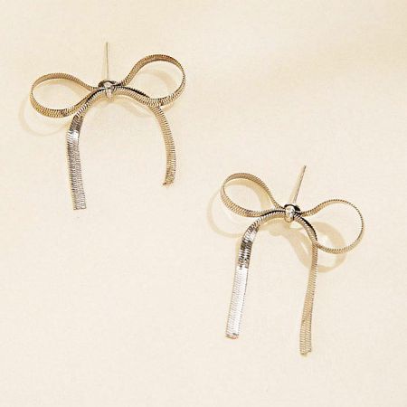 Detailed product shot of the silver bow-shaped earrings against a white background.
