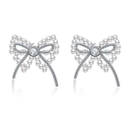 Pearl Ribbon Bow Pierced Earrings - A pair of Pearl Ribbon Bow Pierced Earrings in rhodium-plated brass, showcasing the intricate bow design with a central white pearl and sparkling cubic zirconia accents.