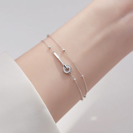 A set of two sterling silver bracelets worn on a wrist, showcasing the layered look.
