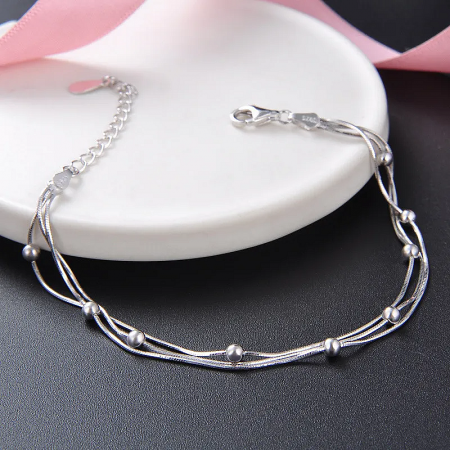 The silver bead bracelet elegantly displayed on a white heart-shaped dish.