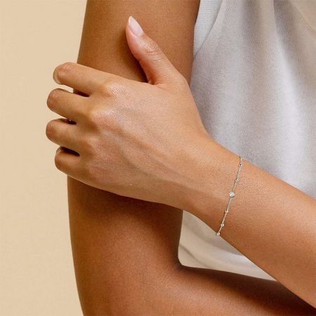 Close-up of the silver bracelet with a circular charm worn on a wrist.