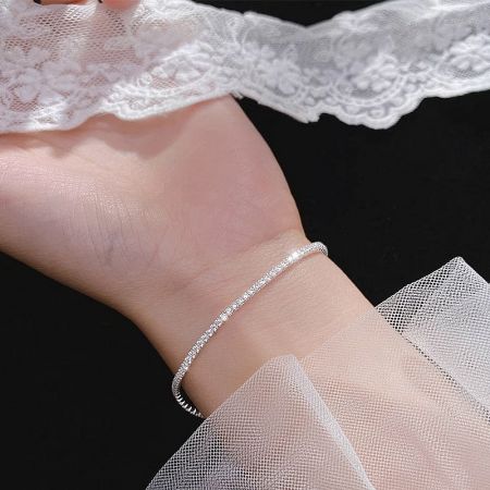 A close-up view of the silver tennis bracelet on a wrist, emphasizing its delicate and elegant design.