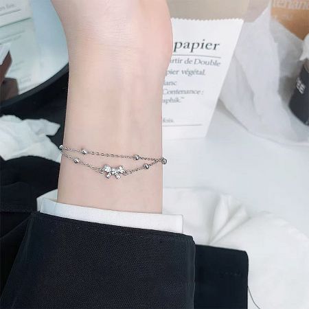 Wholesale Double Layer Coquette Bow 925 Silver Bracelet (Set of 5) - A woman's wrist adorned with the double-layer 925 sterling silver coquette bow stacking bracelets, showcasing their elegant fit.