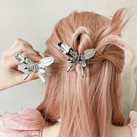 Close-up of the silver butterfly hair clip adding a fashionable accent to pink-colored hair.