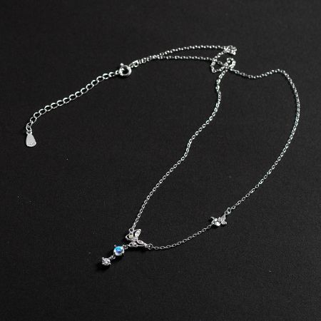 Detailed view of a silver necklace with butterfly and blue stone charms from the collection.