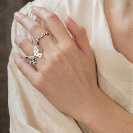 Close-up of a silver butterfly ring paired with a delicate stone band from the set.