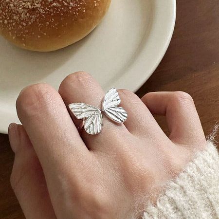 A single sterling silver butterfly ring worn on the index finger, highlighting its craftsmanship.