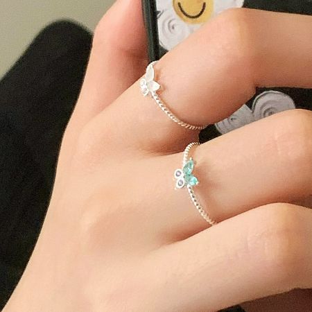 Wholesale 925 Sterling Silver Butterfly Rope Knot Rings Set of 5 - Model's hand wearing two 925 sterling silver rings from the butterfly and rope knot collection, one featuring a light blue gemstone.