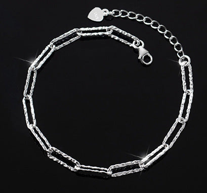 Detail of the silver chain bracelet's secure heart-shaped clasp.