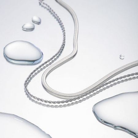 Artistic photo of the silver chain necklaces with water droplets, emphasizing their sleek and waterproof quality.