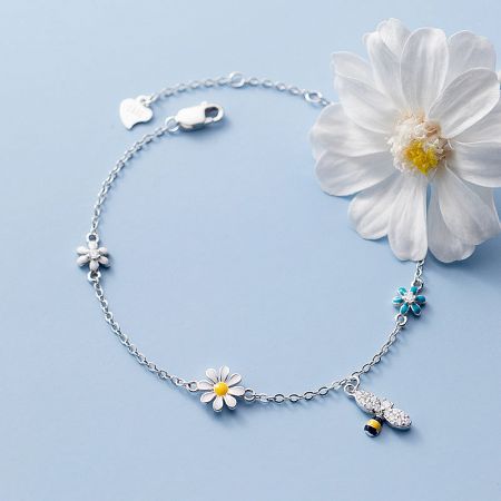 Close-up of the silver version of the daisy and bee charm bracelet, showcasing the intricate details.