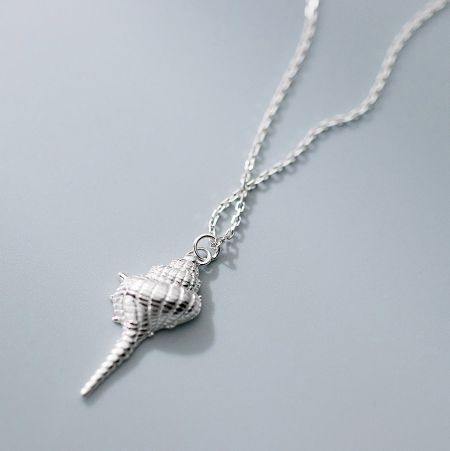 Detailed view of the silver conch shell pendant, showing the fine craftsmanship and twisted chain.