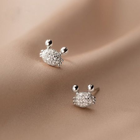 Orecchini a bottone piccoli a forma di granchio in argento sterling 925 con CZ (5 paia) - Un paio di orecchini a bottone a forma di granchio in argento sterling 925, dettagliati in modo intricato con scintillanti pietre di zirconia cubica, esposti su uno sfondo neutro.