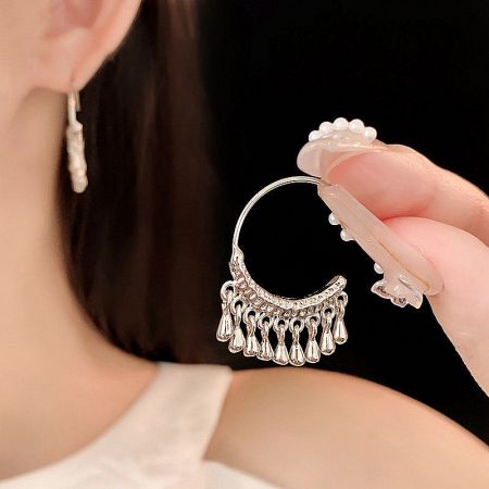 Macro shot highlighting the crescent shape and fringe texture of the silver earring.