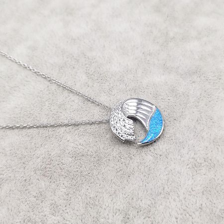 Close-up view of the silver wave pendant with blue inlay and zircon details.