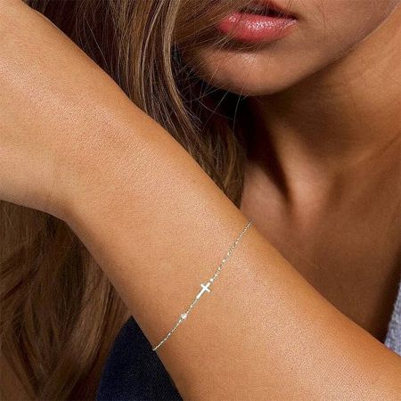Close-up of the 925 sterling silver cross bracelet in a platinum plated finish, worn on a woman's wrist.