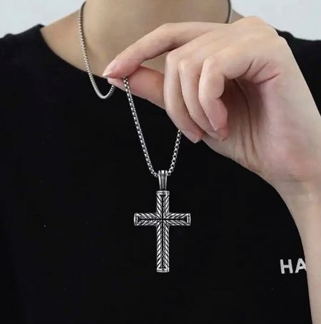 Close-up view of the classic cross necklace held to showcase its detail and finish.
