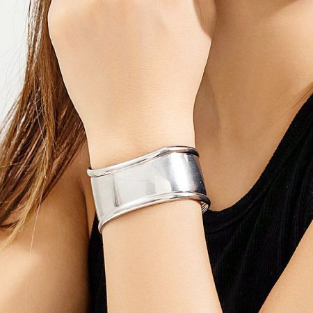 A single silver punk cuff bracelet worn on a woman's wrist for a minimalist look.