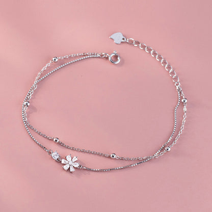 The silver double-strand bracelet worn on the wrist, highlighting its delicate design.