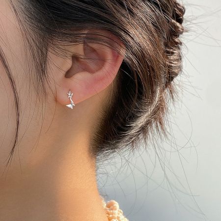 Detailed view of a silver earring from the kawaii set on a model's ear, highlighting the intricate design.
