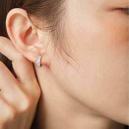Close-up of the platinum-plated pave huggie earring being worn, showcasing its comfortable fit.