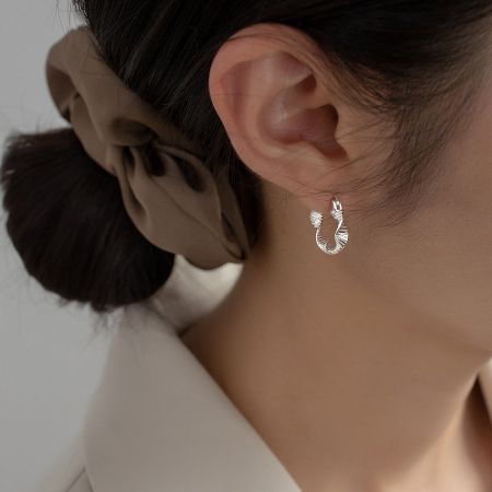 Close-up of a woman wearing a twisted sterling silver hoop earring, highlighting its fit and style.