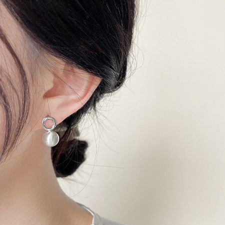 Close-up of the matte silver 3D ball stud earring being worn, showcasing its size and finish.