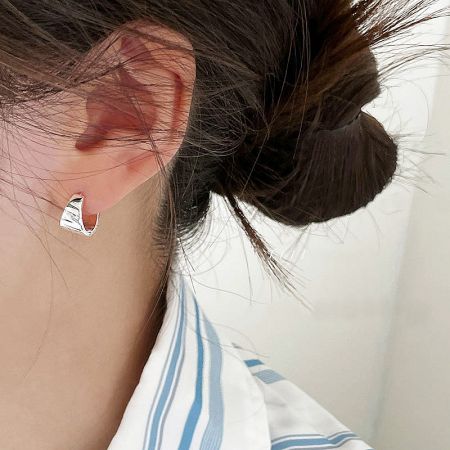 Close-up of a woman wearing the polished sterling silver wide hoop earring.
