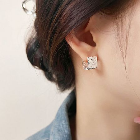 Side profile view of a woman wearing the sleek geometric silver huggie earring.