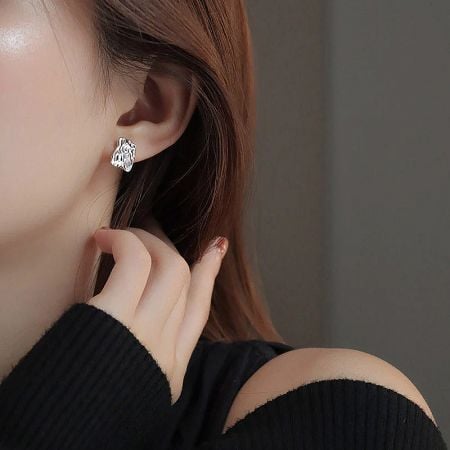 Model showcasing a silver-plated abstract design stud earring.