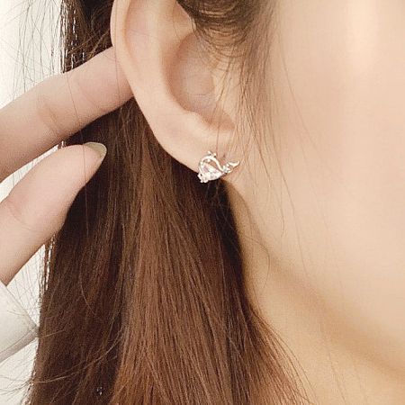 A model showcasing a silver huggie earring with a clear gemstone, illustrating the white variant of the set.