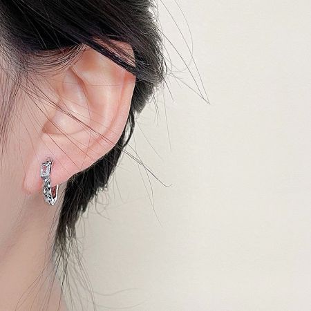 Close-up view of the silver hammered zircon huggie hoop earring.