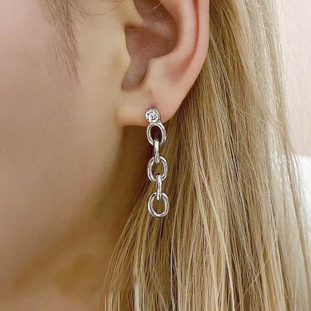 Model showcasing a silver earring with interlocking rings and a central gemstone, demonstrating its stylish appeal.