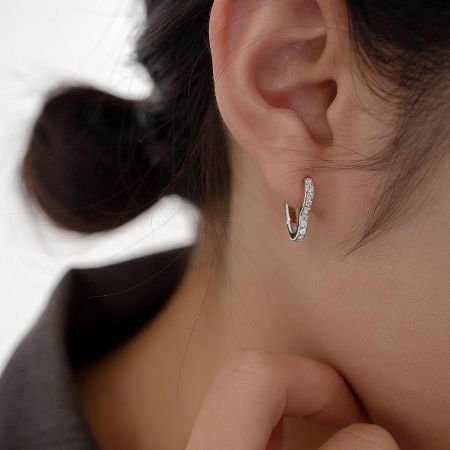 Close-up of a woman wearing the sterling silver heart hoop earring to showcase its size and sparkle.