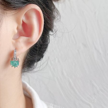 Side view of the silver huggie earring with a light blue-green gemstone.
