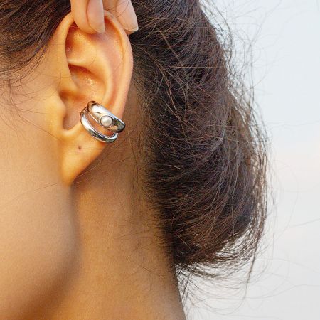 Close-up of the silver stainless steel pearl ear cuff worn on an ear.