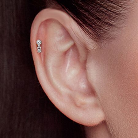 Close-up of the sterling silver two-stone stud earring worn on the ear.