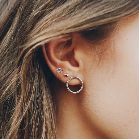 A curated ear look featuring multiple 925 sterling silver earrings, including a hoop, bird stud, and sunburst design.