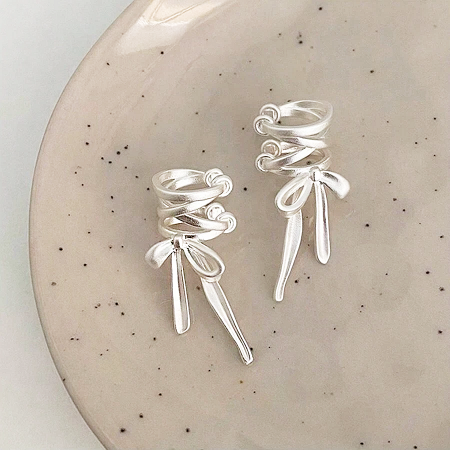 925 Sterling Silver Matte Bowknot Tie-Bow Ear Cuff Earrings (5 Pairs) - A pair of 925 sterling silver matte bowknot ear cuff earrings with a unique coiled design, displayed on a decorative plate.
