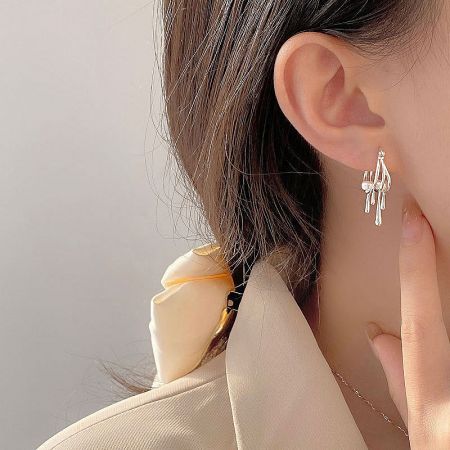 Model wearing the sterling silver pearl drop hoop earrings, paired with other fashion accessories.