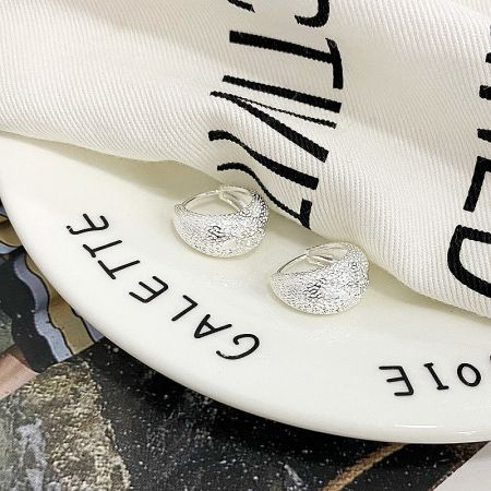 The 925 sterling silver version of the chunky hoop earrings elegantly presented on a decorative plate.