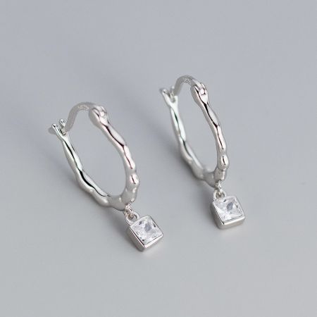 Detailed view of the silver twisted hoop earrings with clear square zircon stones.