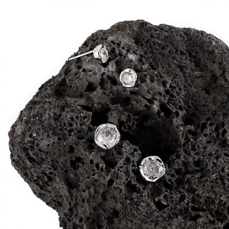 Artistic product shot of the sterling silver CZ stud earrings on a dark rock, emphasizing their high-grade quality.