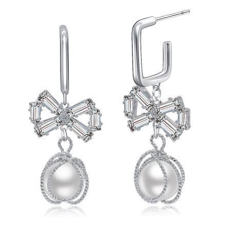 Detailed shot of the silver bow earrings highlighting the floral design with clear stones and a dangling pearl.