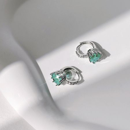 A pair of elegant silver earrings with vibrant green gemstones and sparkling accents.